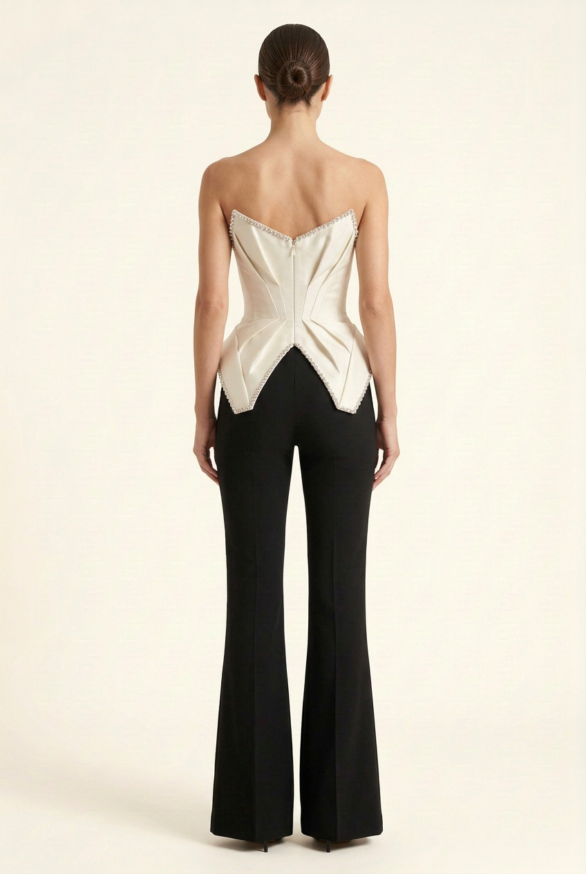Back view of the strapless couture jumpsuit with a sculptural white bodice and black tailored flared pants