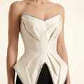 Close-up of the sculptural ivory bodice with clear crystal stones, showing folded fabric and detailed stone placement