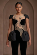 Front close-up of the black-and-champagne couture jumpsuit with sculpted shoulders, wave detailing, and peplum