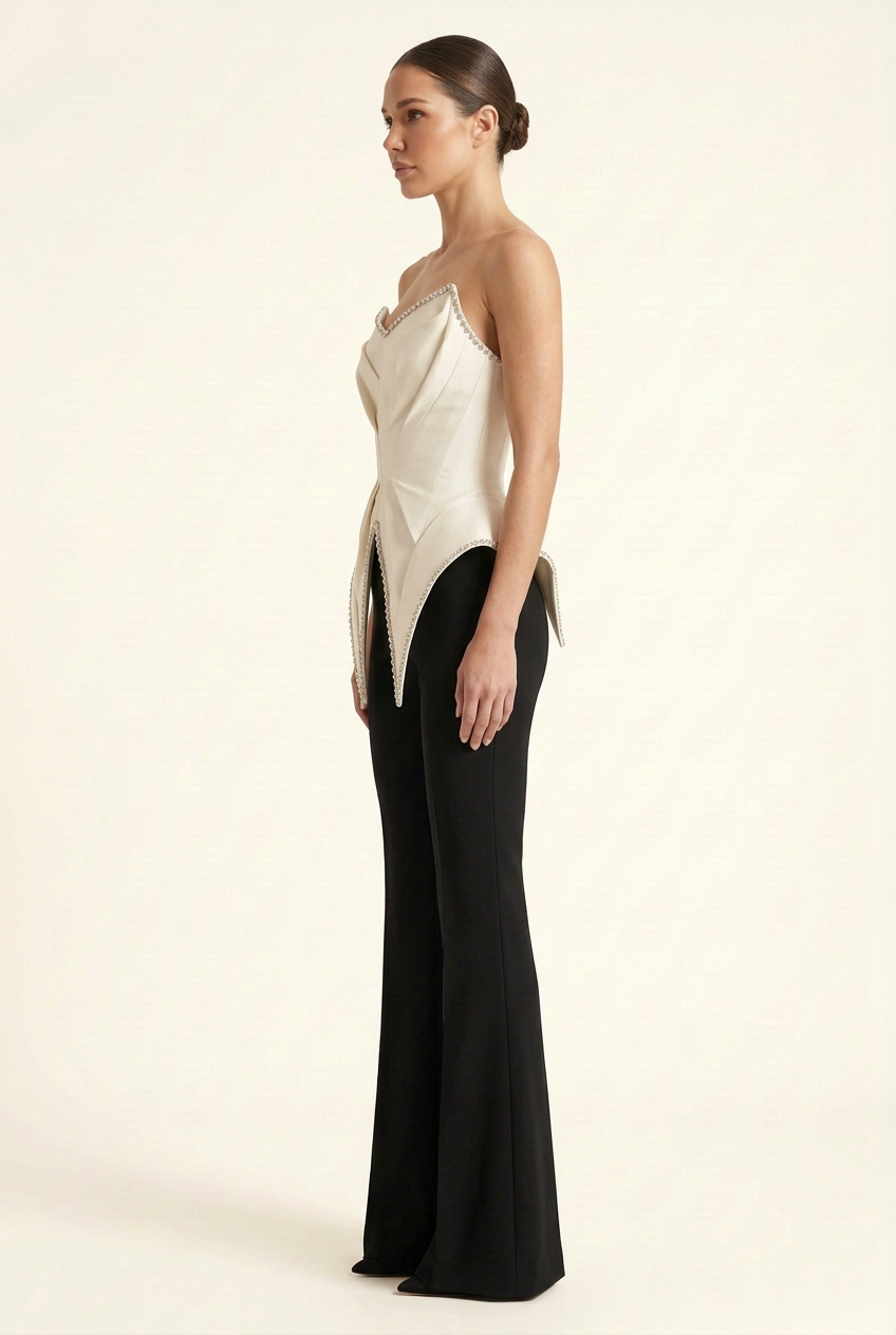 Side view of the strapless couture jumpsuit, showing the sculptural ivory bodice and tailored black flared pants